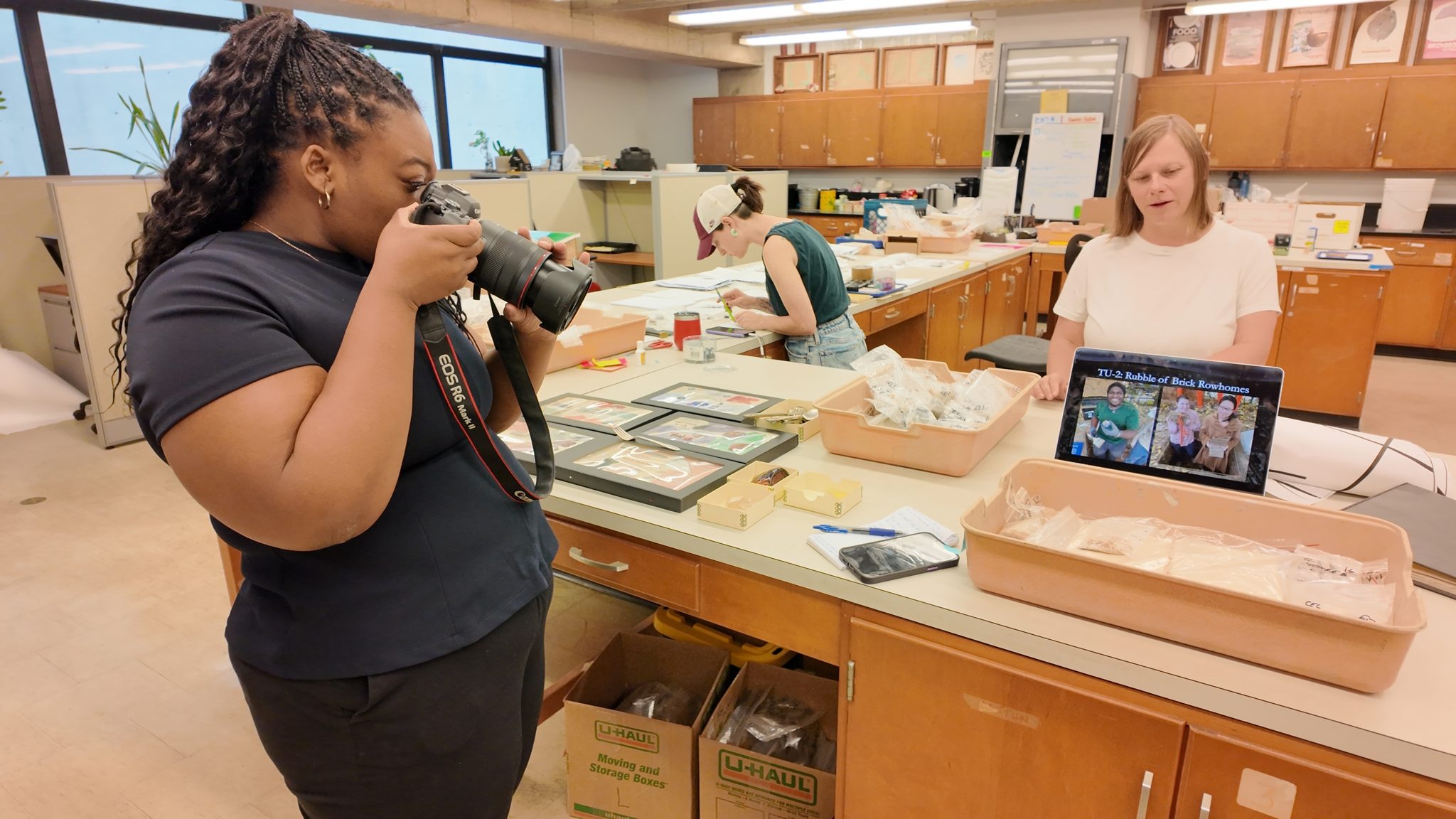 Two fellows compare records over a counter stacked with files and a laptop.