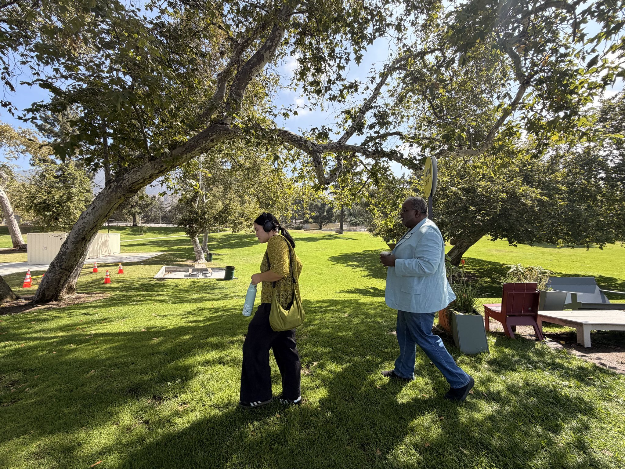 A fellow walks with an interview subject beneath a sprawling oak.