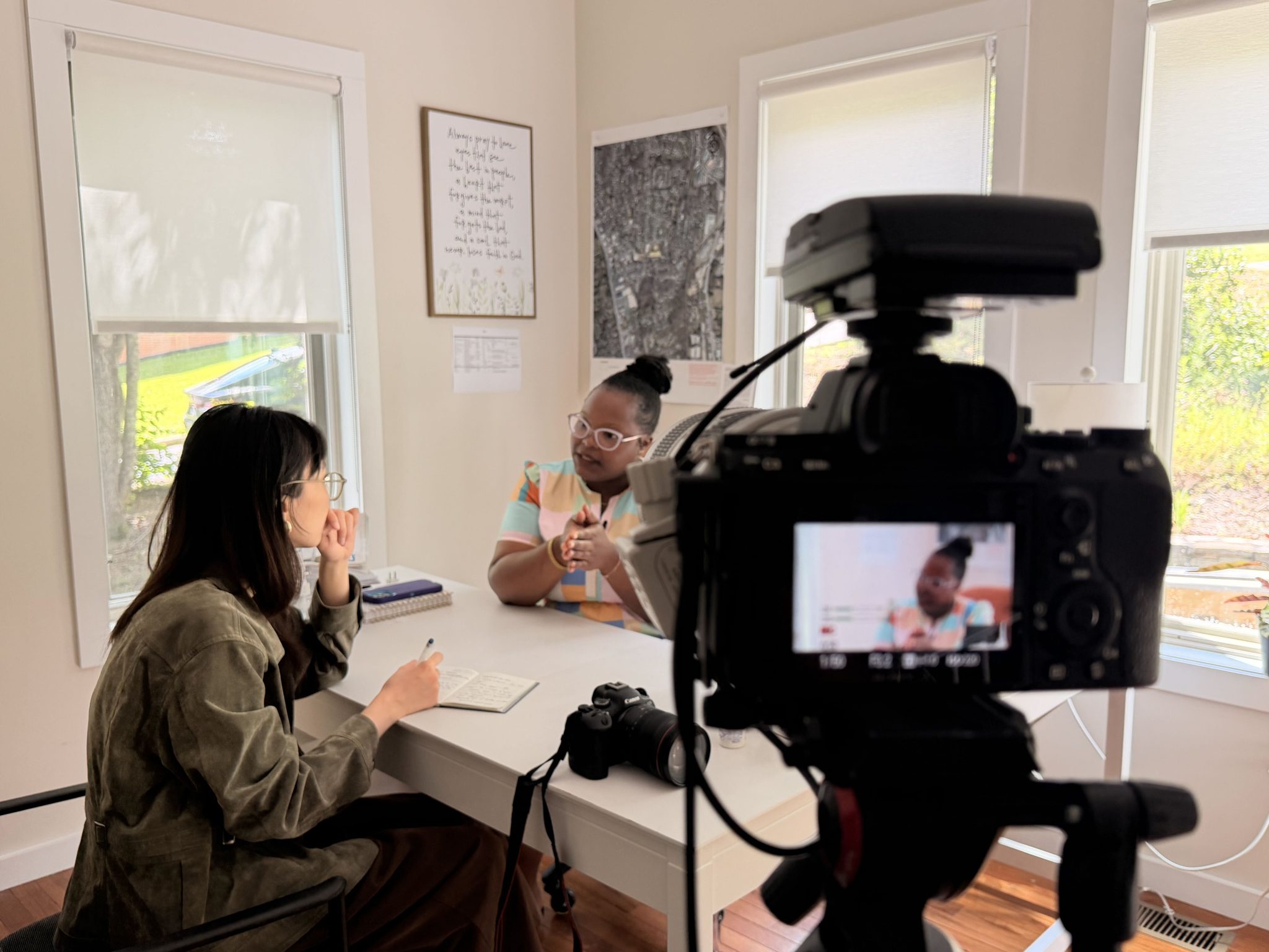 A fellow interviews a man on camera in his living room.