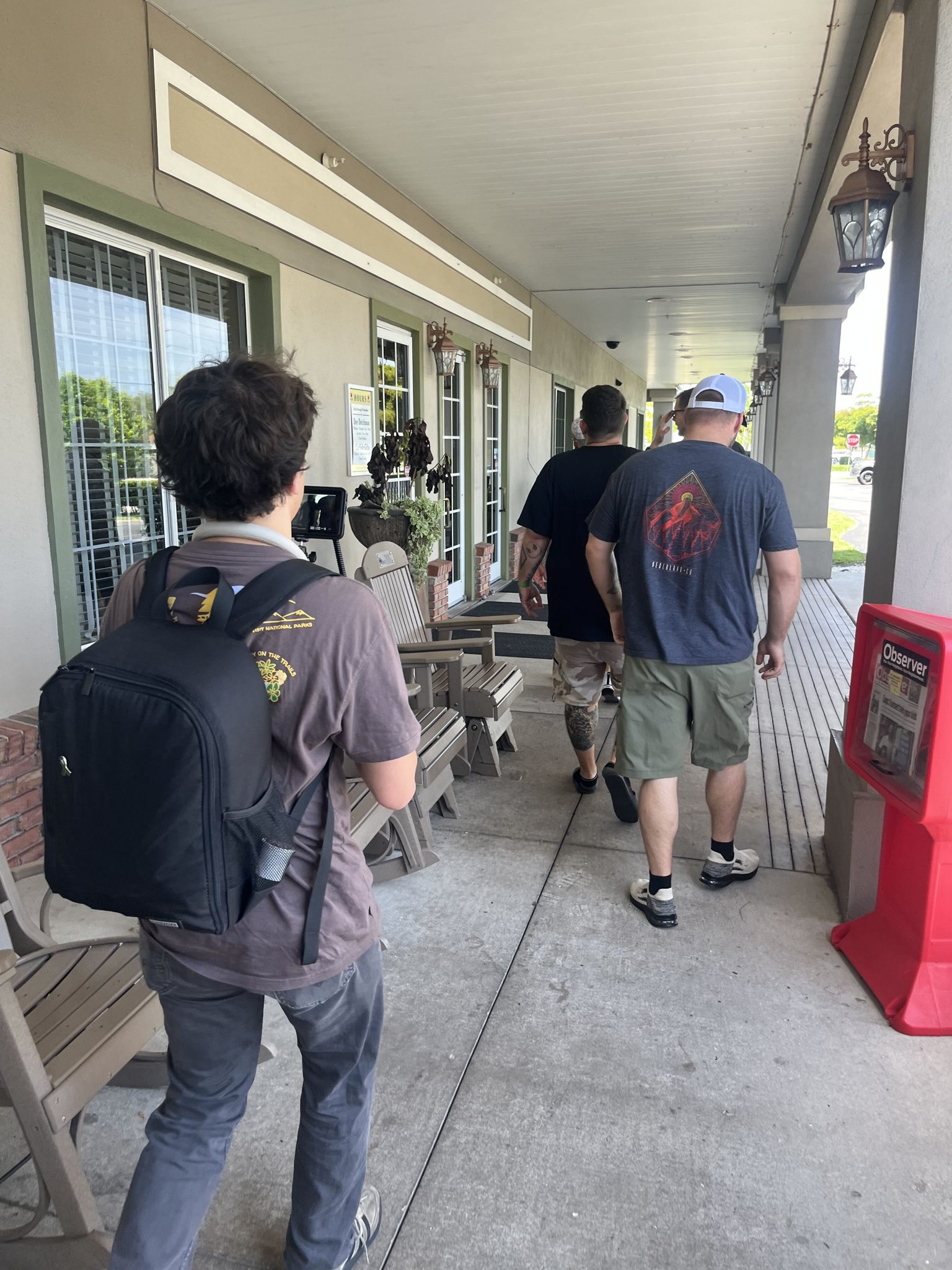 Fellows walk down a long covered walkway with their gear.
